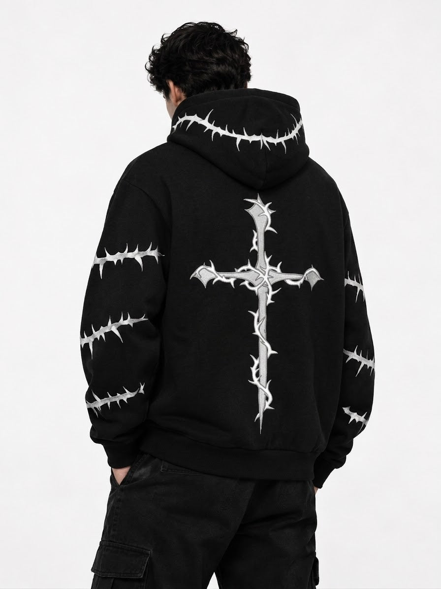 A person shown from the back wearing a black hoodie with a large white thorny cross graphic on the back and smaller thorny line graphics along the hood and sleeves, paired with black cargo pants against a plain light background.
