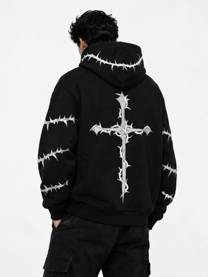 A person shown from the back wearing a black hoodie with a large white thorny cross graphic on the back and smaller thorny line graphics along the hood and sleeves, paired with black cargo pants against a plain light background.